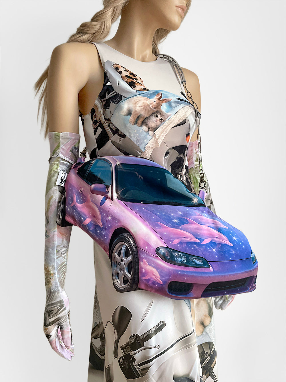 Mannequin wearing a sleeveless printed top and long skirt with a handbag resembling a pink sports car.