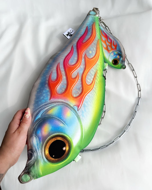 Hand holding Trophy Fish Bag in regular size, showing fish design and fiery pattern.