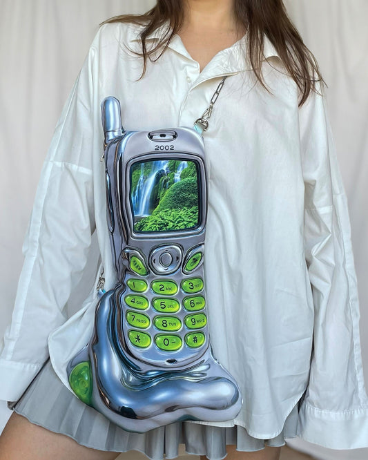 Model wearing the Nature Cell Bag – oversized silver phone-shaped handbag by Chimera Lab with chain strap and nature screen design