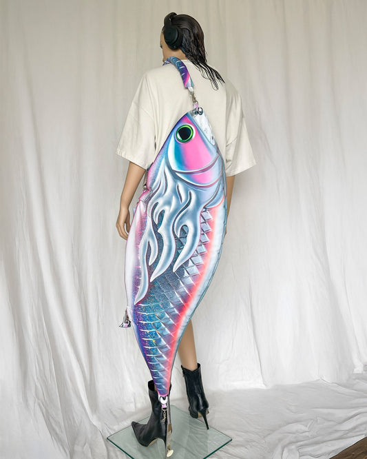 Model wearing oversized fish-shaped bag with surreal 3D effect and padded straps.