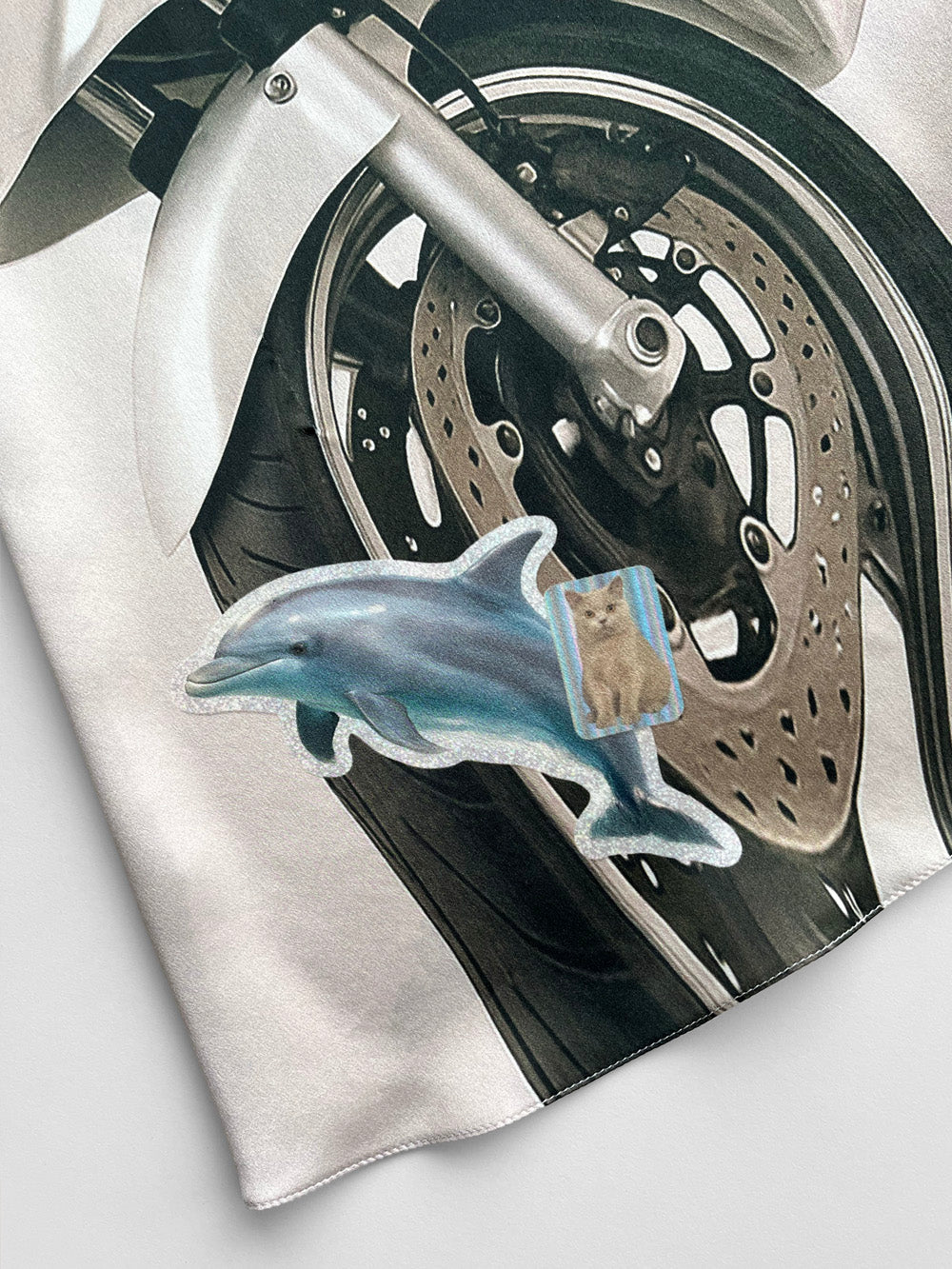 Close-up of a motorcycle wheel with a dolphin and cat sticker print on a white background.
