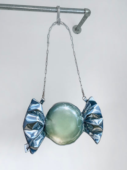 Metallic candy-shaped crossbody bag with a chain on a white background.