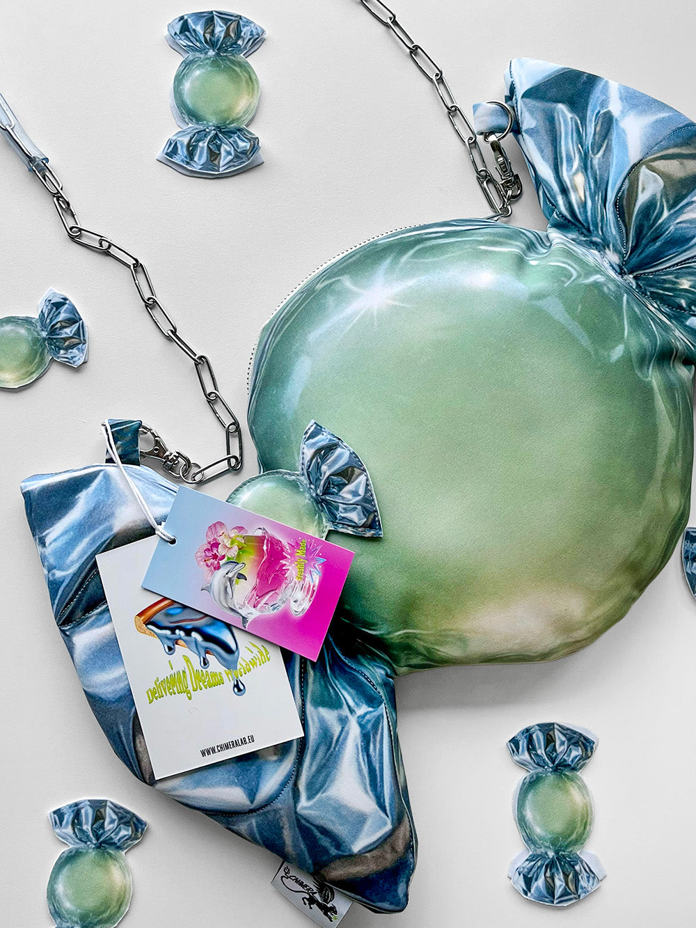 Green and metallic candy print handbag with accessories on a light background.