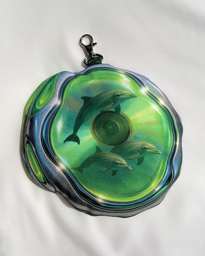 Close-up of the back of the DOLPH MP3 pouch bag by Chimera Lab, featuring a surreal dolphin vocal CD print inside translucent green casing.