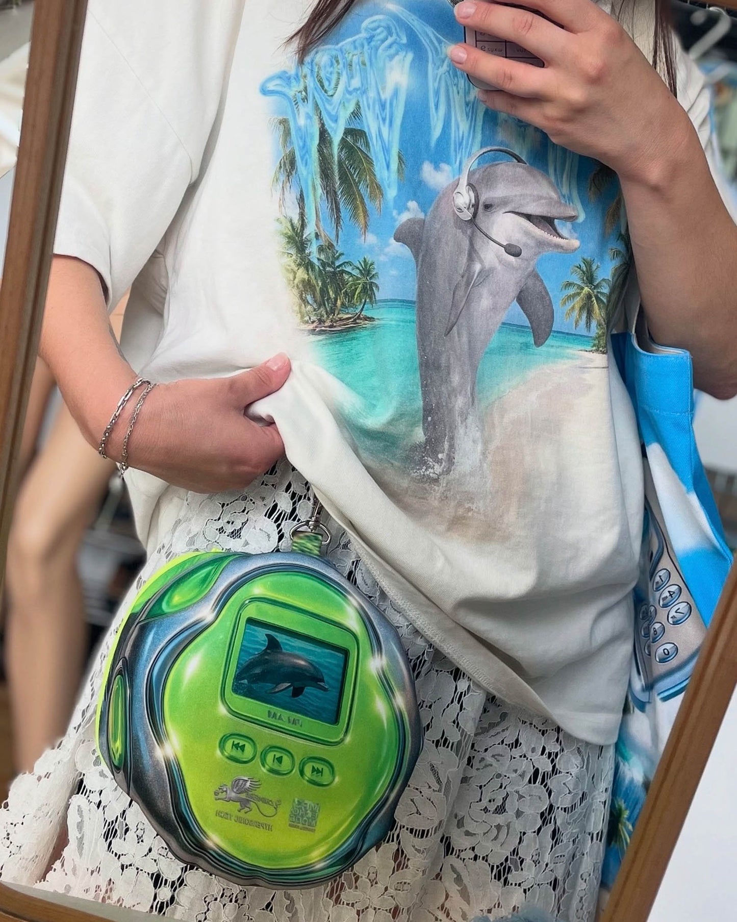 Model wearing the DOLPH MP3 pouch bag by Chimera Lab, a retro-inspired dolphin print bag with stainless steel chain, styled with a dolphin graphic T-shirt.