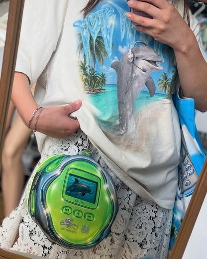 Model wearing the DOLPH MP3 pouch bag by Chimera Lab, a retro-inspired dolphin print bag with stainless steel chain, styled with a dolphin graphic T-shirt.