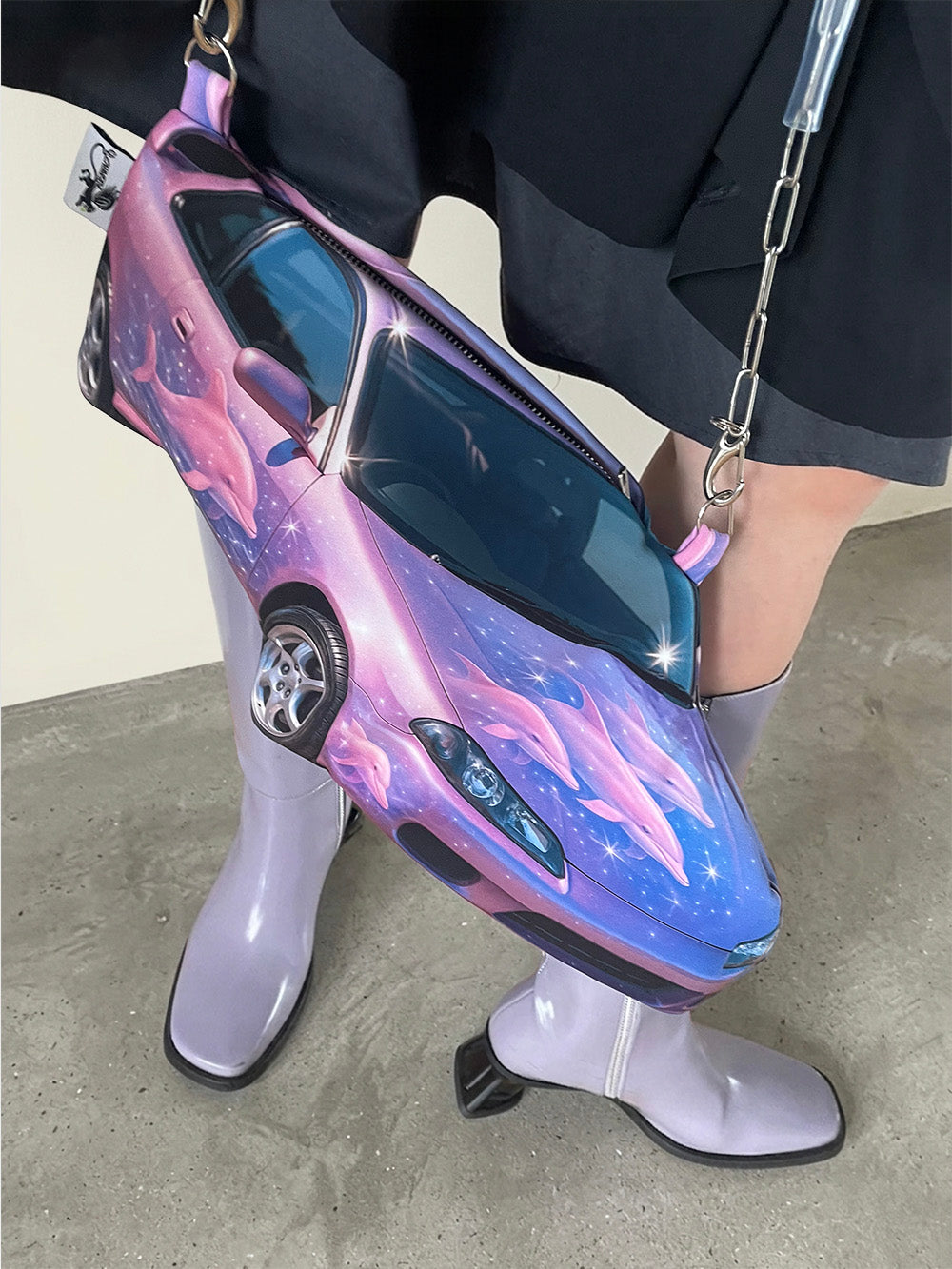 Car-shaped handbag with a futuristic design worn by a person.
