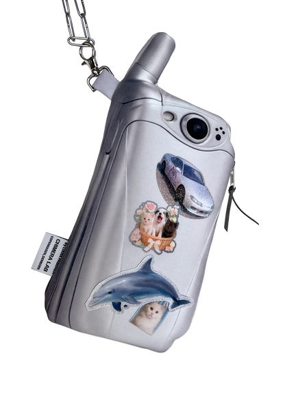 A silver flip phone-shaped zipper pouch with a carabiner clip, decorated with stickers of a car, a dog, a cat, and a dolphin, shown on a plain white background.