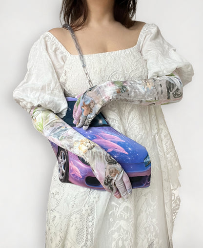 Person wearing a white lace dress with long printed opera gloves, holding a purple car print bag.