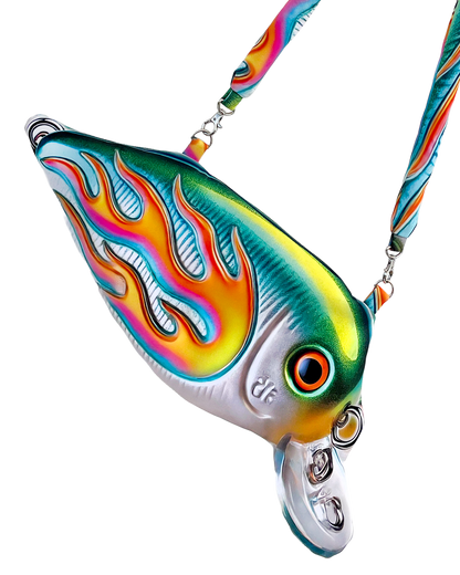 Close-up of the Moto Fish Bag by Chimera Lab, shaped like a 3D fishing lure with a chrome body and neon flame graphic, featuring a padded printed strap.