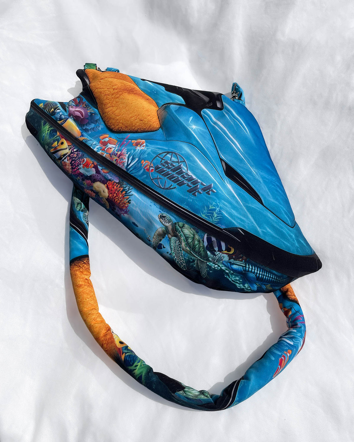 Chimera Lab x Sharkwork turquoise Jet ski-shaped bag featuring aquatic coral reef print and sea turtle, laid flat on white background