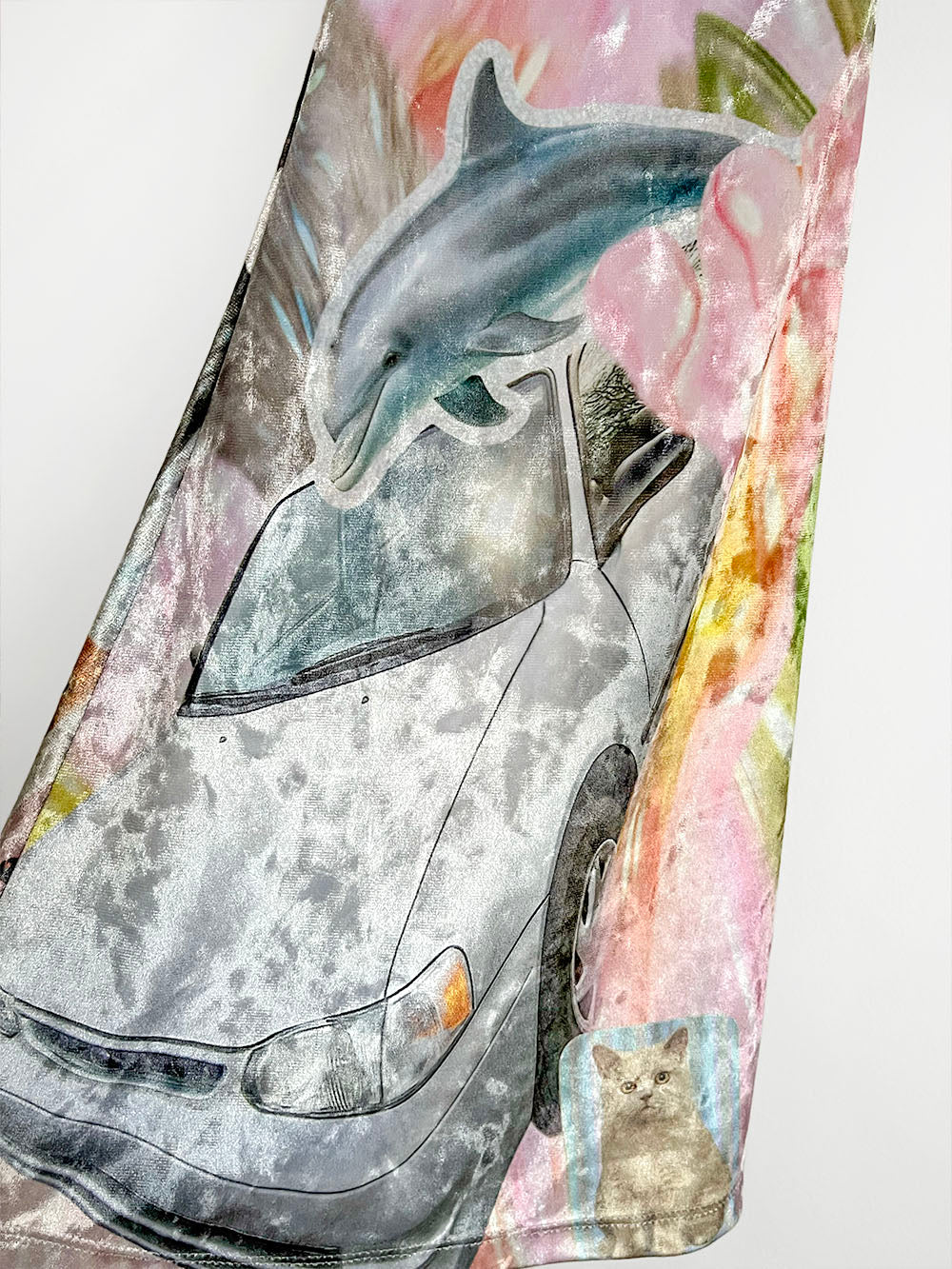 Close-up fabric with dolphin, car, and cat Y2K sticker print design on a watercolor background.