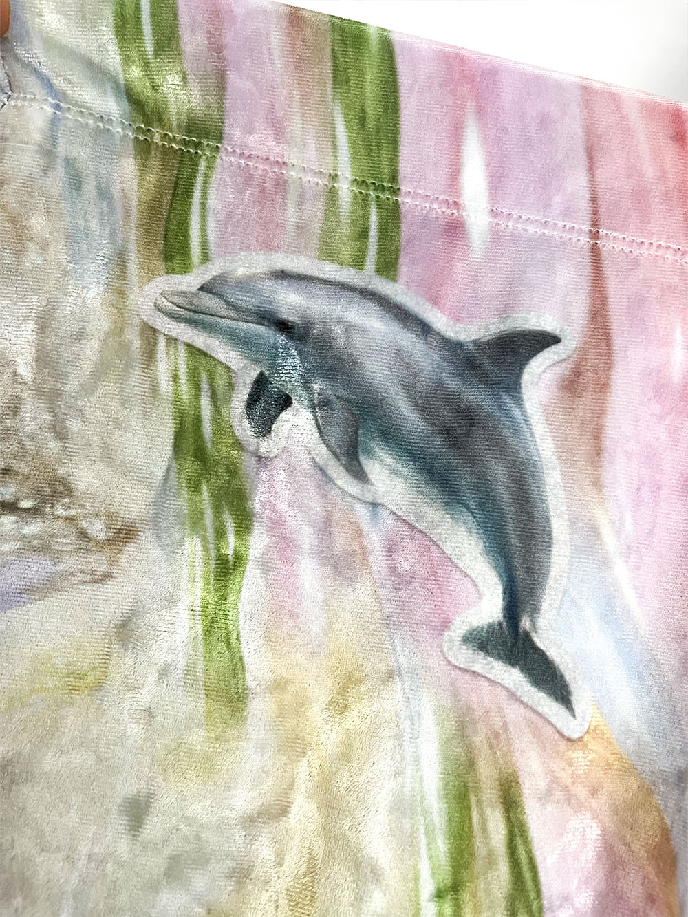 Dolphin sticker print design on a colorful fabric background.