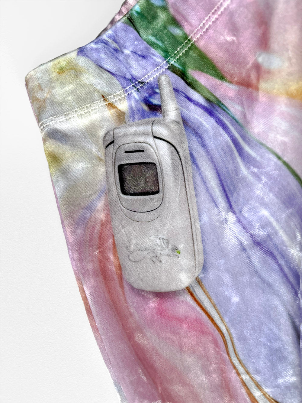 Silver flip phone print close-up on a colorful fabric background.