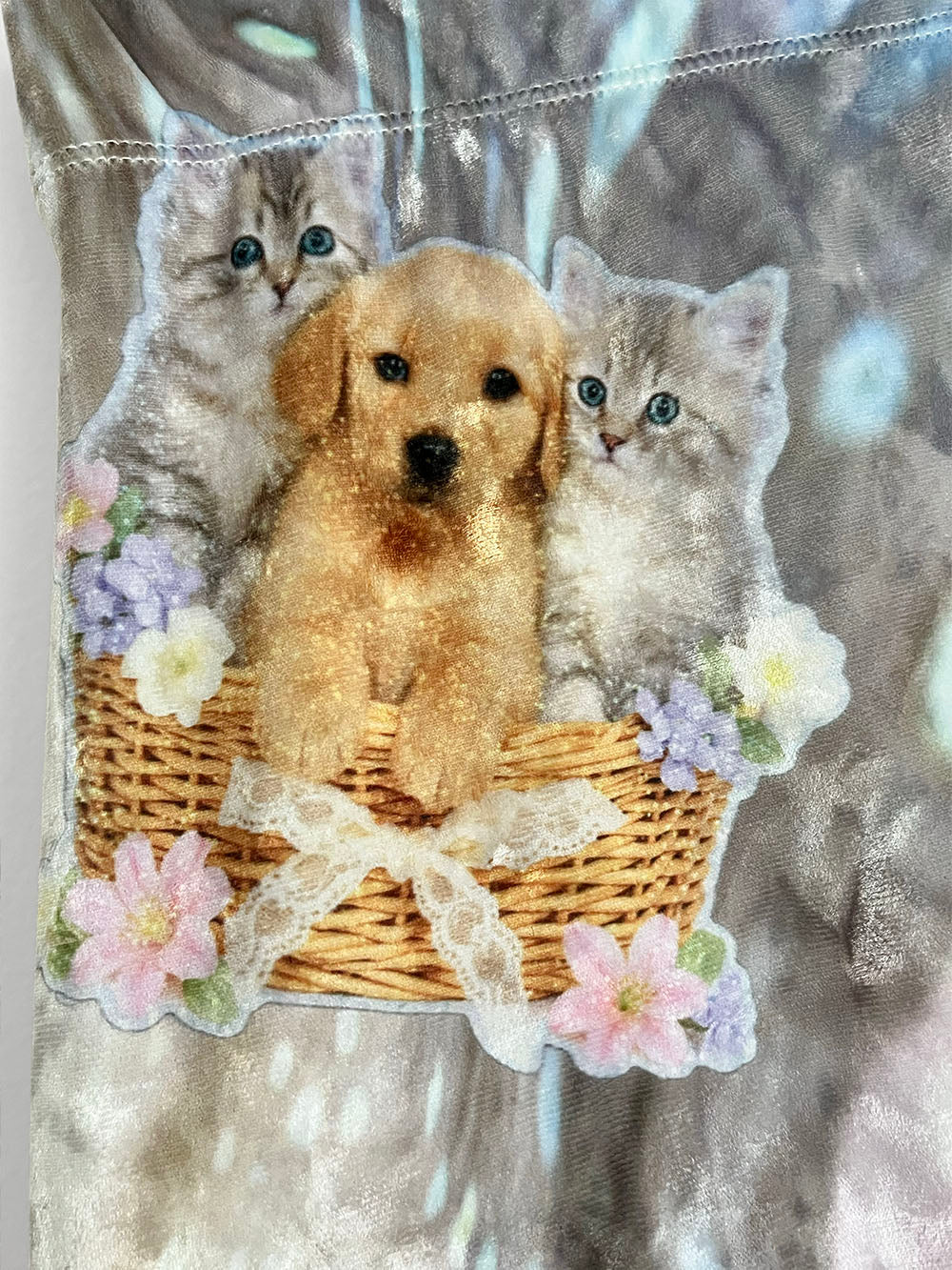 Decorative fabric with a golden retriever puppy and two kittens in a basket, surrounded by flowers.