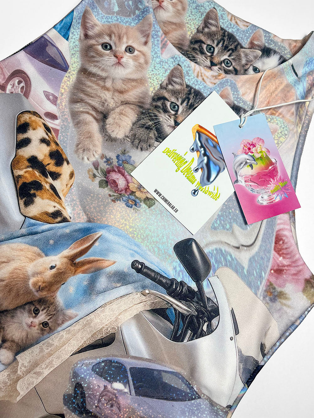 Close-up of a tank top featuring a motorcycle print with cute cats and bunnies, and two small CHIMERA brand tags.